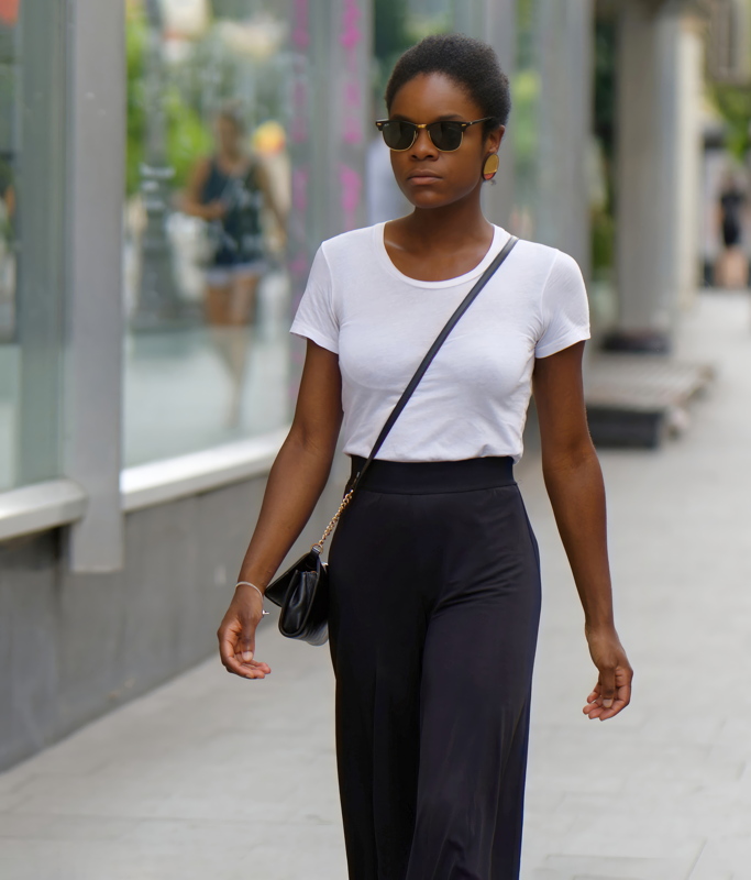 13 - A person wearing a classic white t-shirt and wide-leg black trousers paired with sunglasses and a crossbody bag